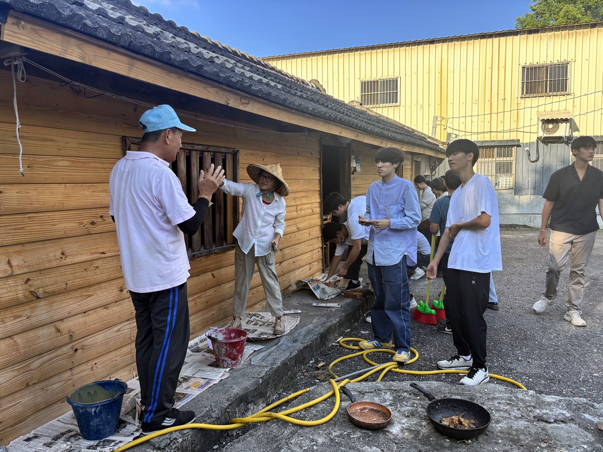 學生詢問老木屋的故事,戴藍色鴨舌帽的是邱文正先生,戴斗笠的是鍾寶珠常務理事