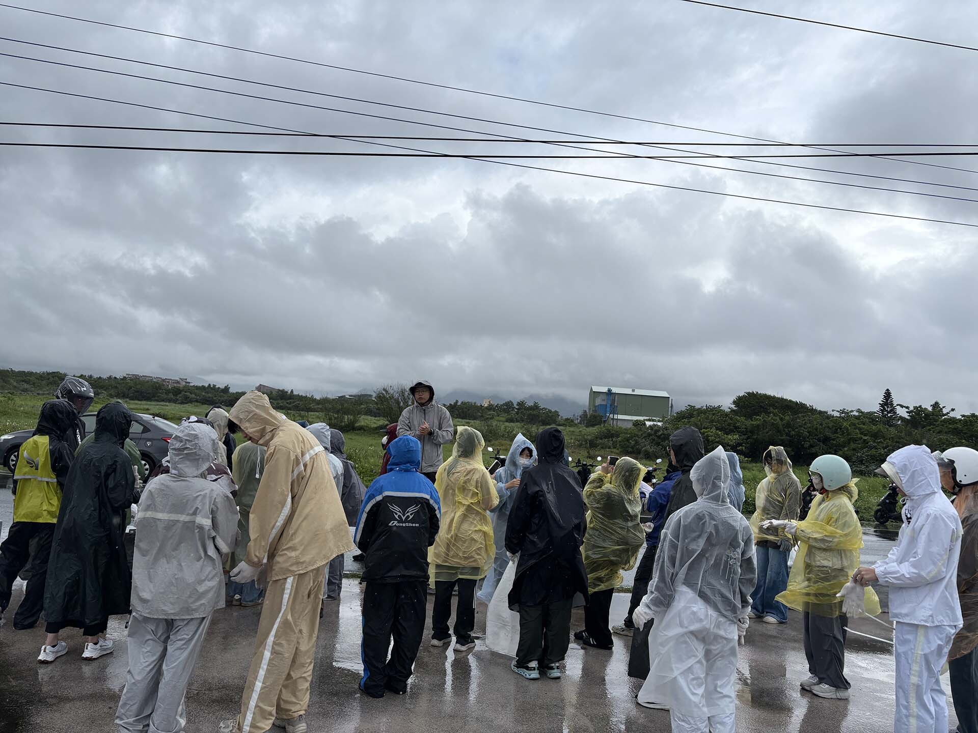 風雨中聽黑潮海洋基金會林東良執行長(中間戴帽者)說明ICC淨灘方式